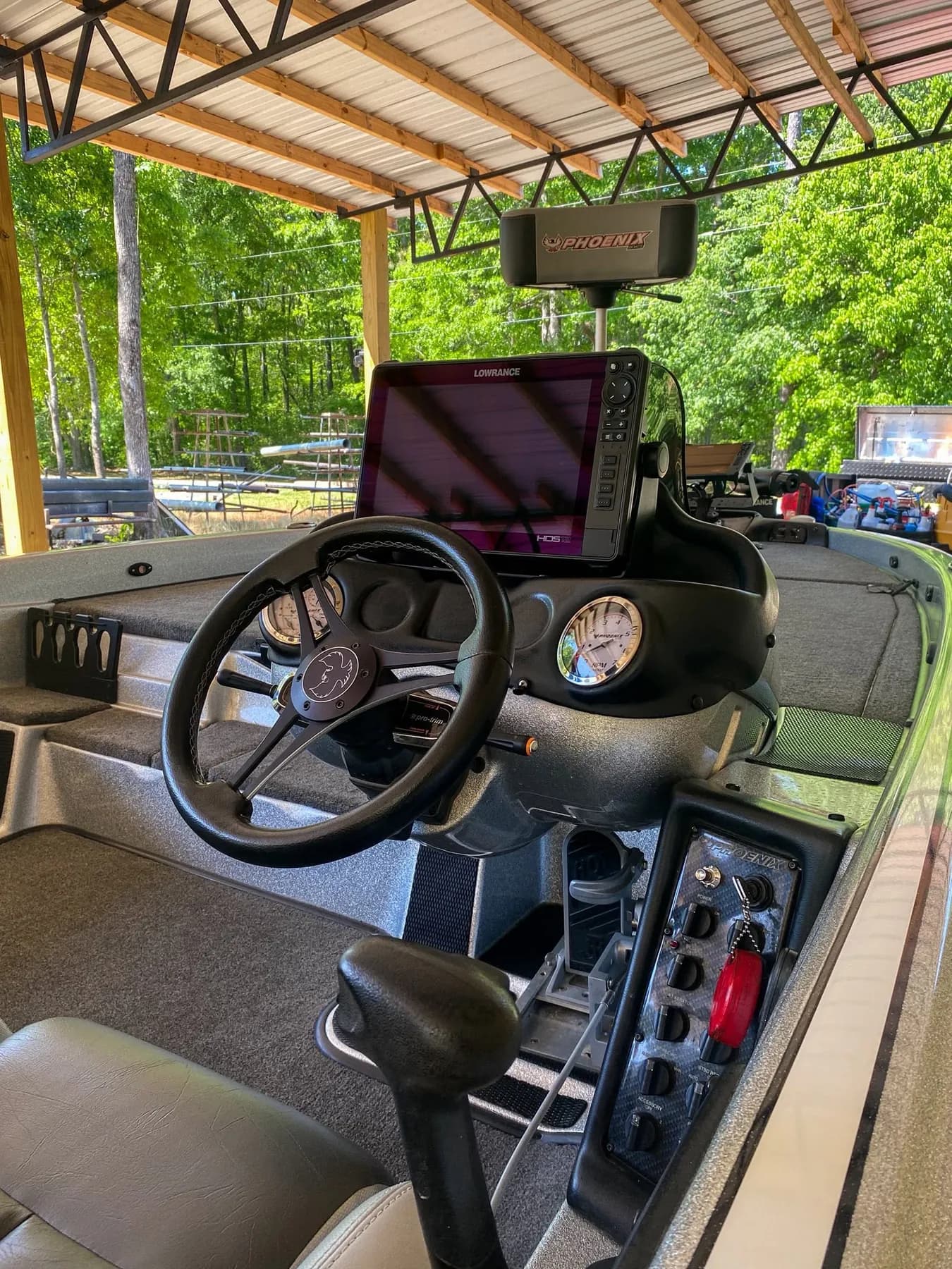 Bass boat console with a large fish finder display, steering wheel, gauges, and switch panel