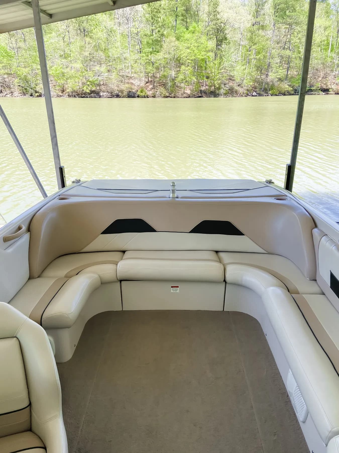 Clean cream and tan seating and carpeted deck of a bowrider in a covered slip on a lake