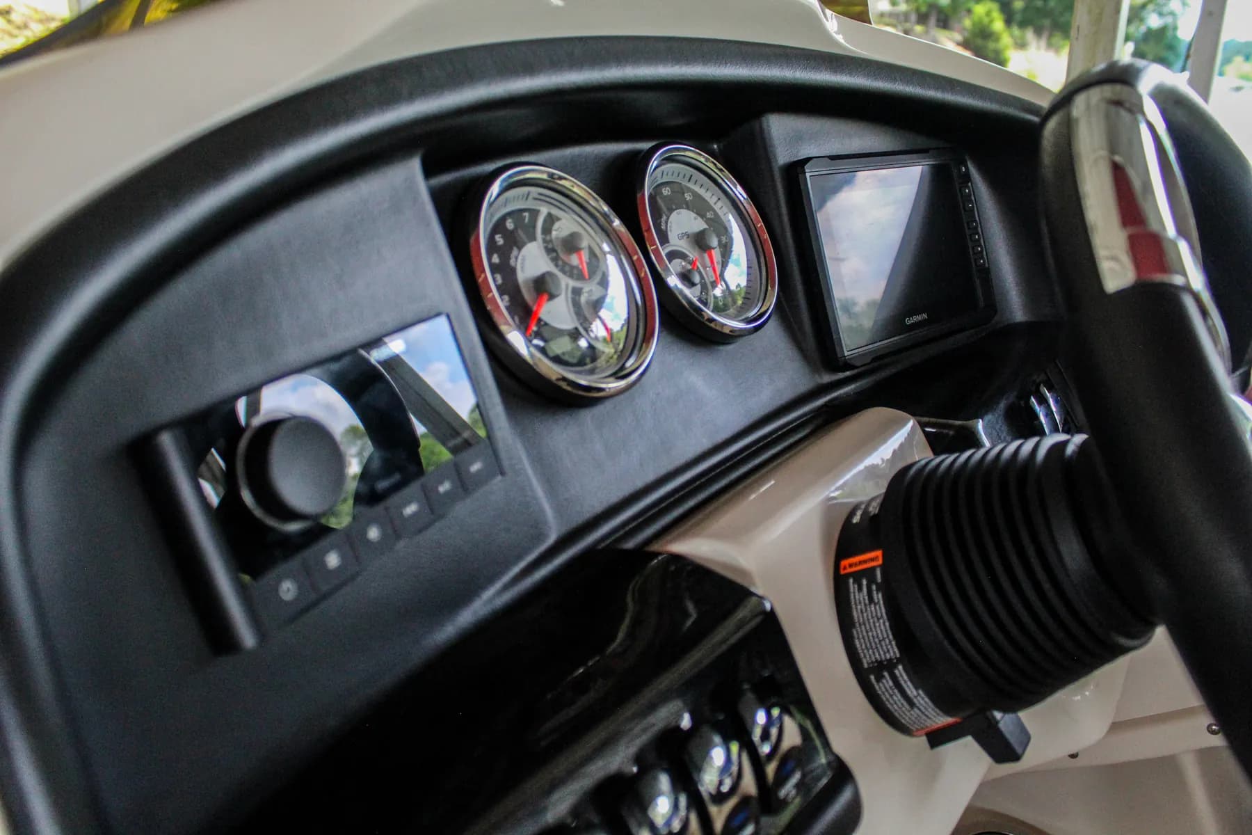 Pontoon helm dash with a marine stereo, gauges, and a Garmin chartplotter
