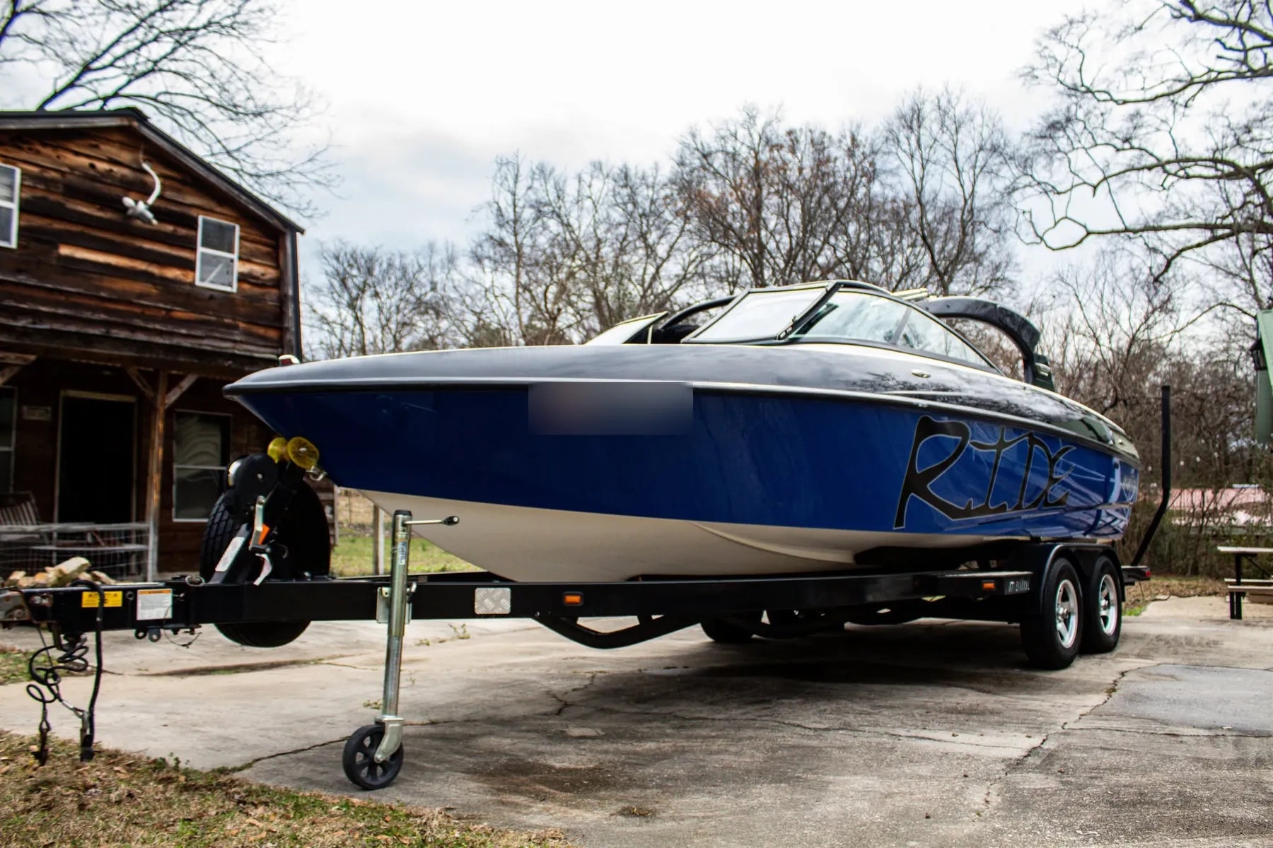 Blue and black wake boat on a trailer in a driveway